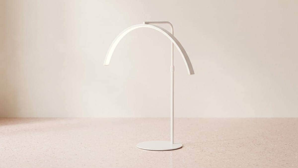Lampe demi-lune LED blanche sur pied, l'arc lumineux incliné au sommet d'un mât fin posé sur un socle rond