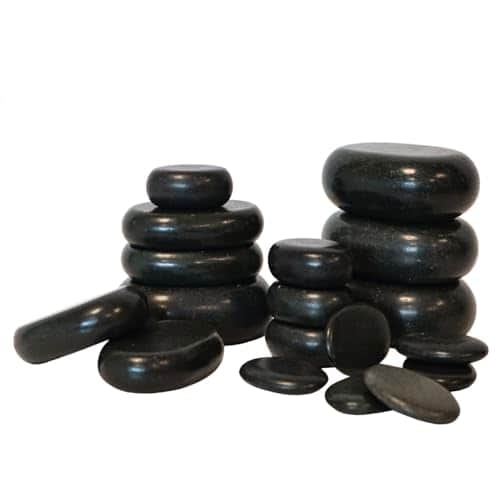 Pierres de basalte noires et lisses de plusieurs tailles, empilées en colonnes, avec quelques petites pierres plates au premier plan