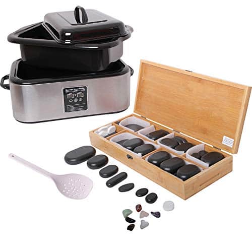 Chauffe-pierres rectangulaire en inox à bac et couvercle noirs, louche blanche, long coffret en bambou ouvert sur des pierres noires et blanches, et petites pierres de couleur au premier plan