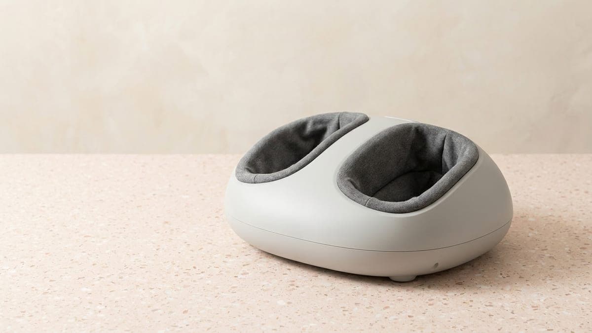 Appareil de massage des pieds gris clair aux formes arrondies, avec deux cavités garnies de tissu gris