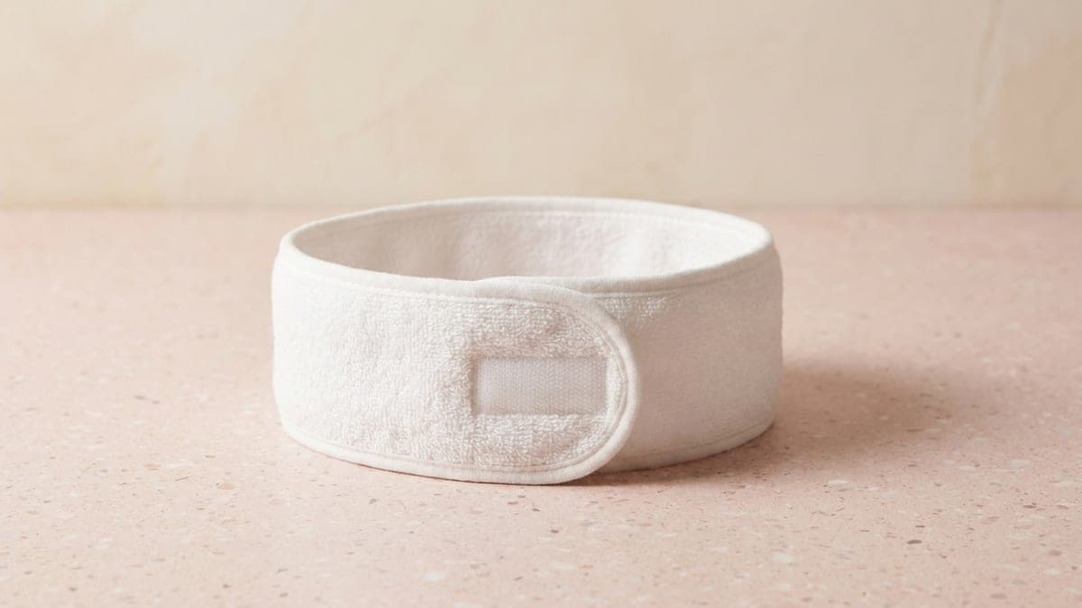 Bandeau de soin en éponge blanche, fermé par une bande auto-agrippante, posé sur un plan en terrazzo rose