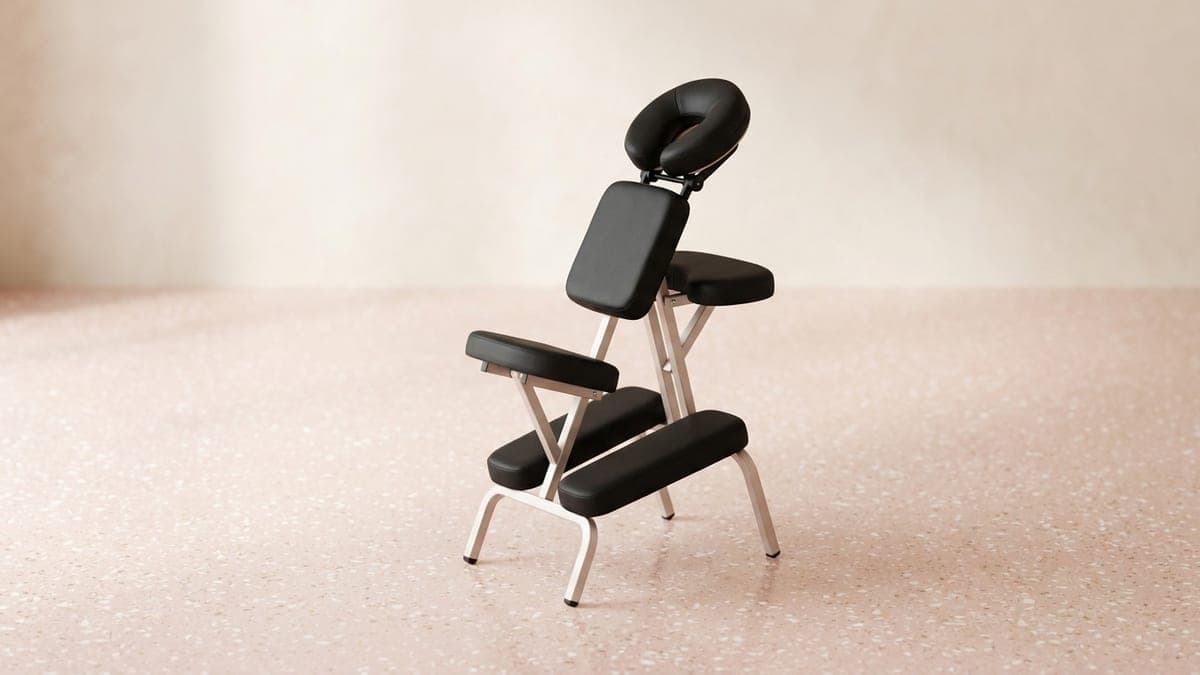 Chaise de massage assis pliante à coussins noirs, avec têtière, appui-poitrine, accoudoir et appuis pour les genoux, sur un cadre en métal clair