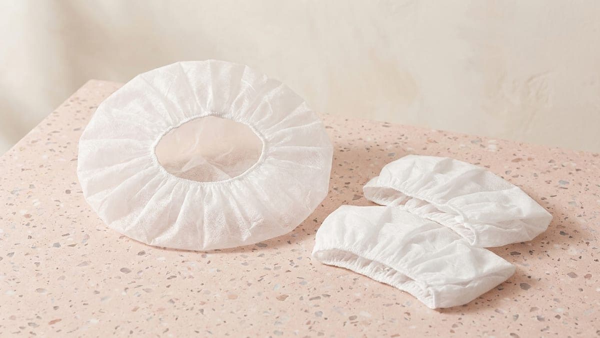 Trois charlottes jetables en non-tissé blanc, une ouverte et deux repliées