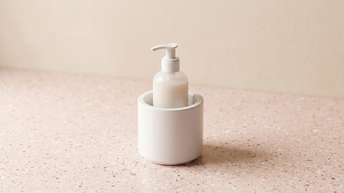 Chauffe-flacon cylindrique blanc dans lequel est posé un flacon à pompe blanc