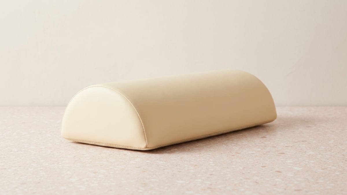 Coussin demi-lune en similicuir crème posé sur sa face plane