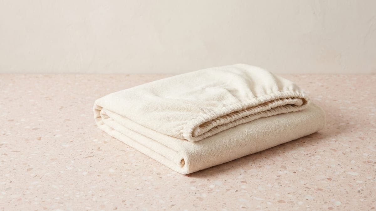 Drap-housse en éponge crème plié, bord élastiqué visible