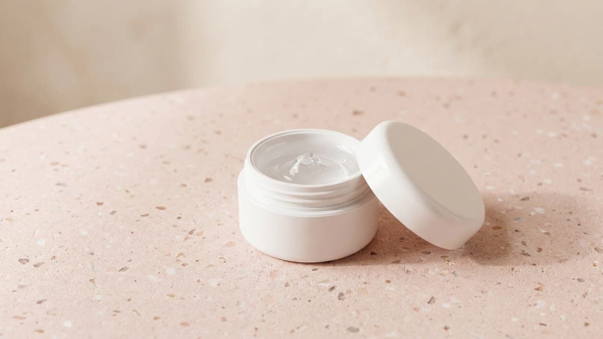 Pot ouvert de gel de construction transparent pour ongles, couvercle posé à côté