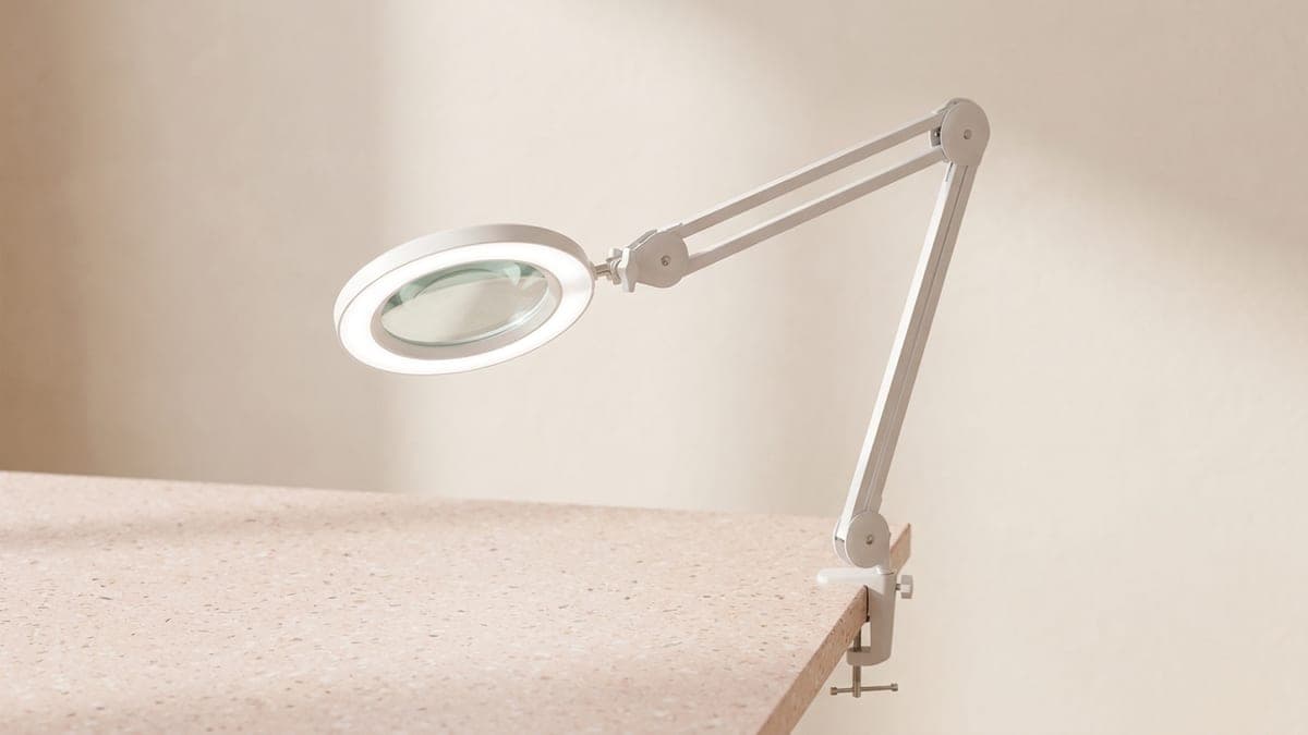 Lampe loupe blanche, lentille ronde cerclée de LED, sur bras articulé fixé par une pince