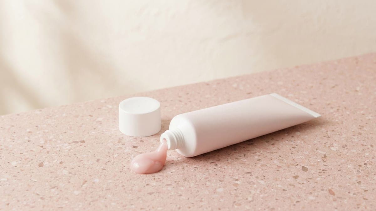 Tube de polygel ouvert, une noisette de gel rose sortie du tube
