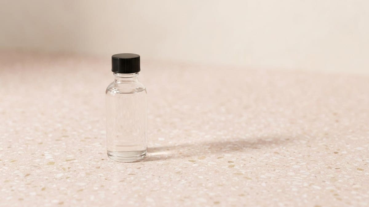 Petit flacon en verre transparent à bouchon noir, rempli d'un liquide incolore