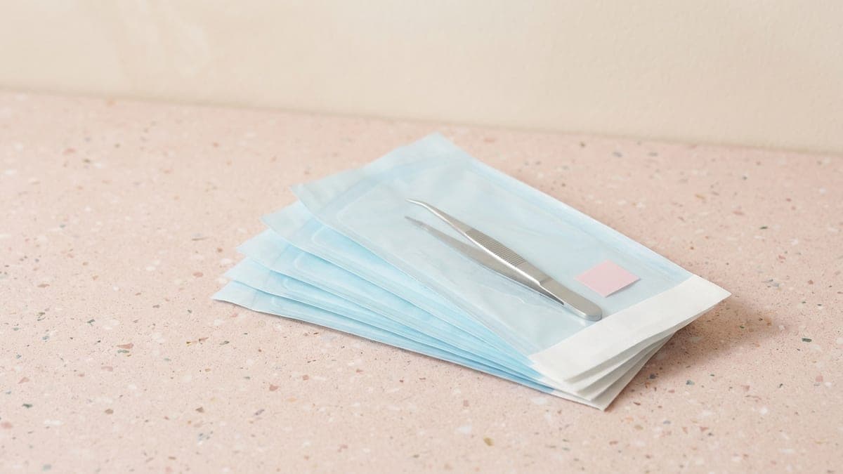 Sachets de stérilisation bleu pâle en éventail, une pince en inox dans celui du dessus