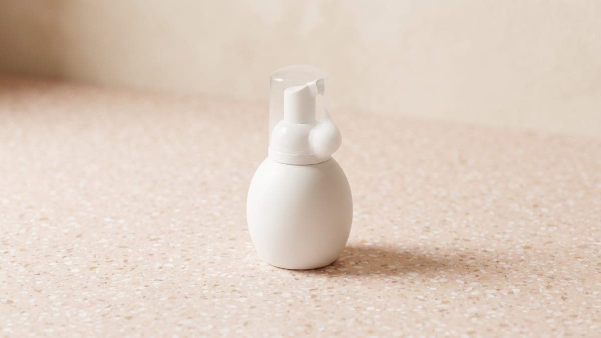 Petit flacon blanc à pompe moussante, un peu de mousse au bec