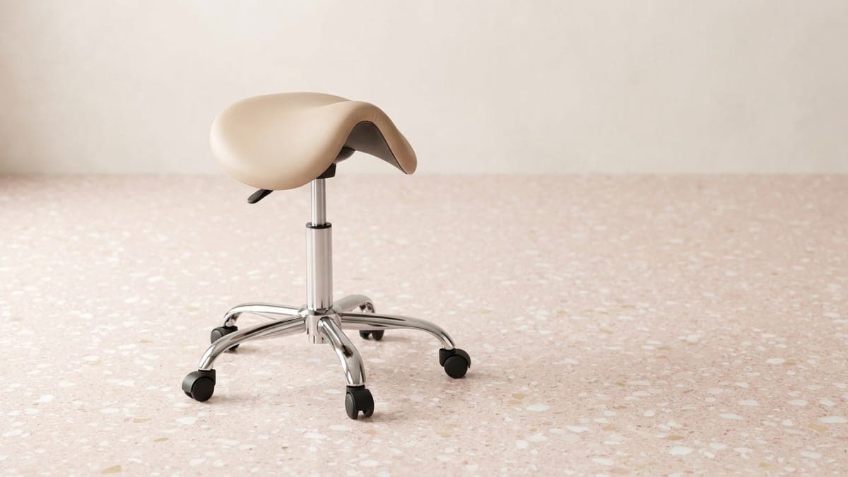 Tabouret selle à roulettes, assise en simili-cuir beige et piétement chromé