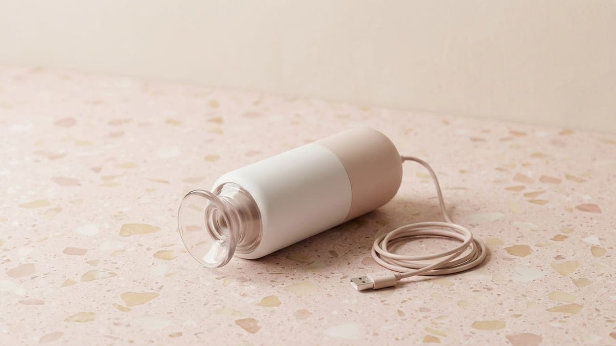 Appareil de massage par aspiration blanc et rose, tête-ventouse transparente et câble de recharge